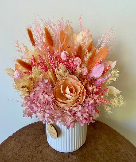 Sherbet is created using dried, preserved and faux flowers and displayed in a ribbed ceramic pot. It's vibrant tones of pink and orange will add a little colour to any room in the home or office and is also the perfect size for Nursing Homes and Hospitals. Approx size is 30cm x 20cm including pot. Sutherland shire delivery. Sydney wide delivery. Australia wide delivery.