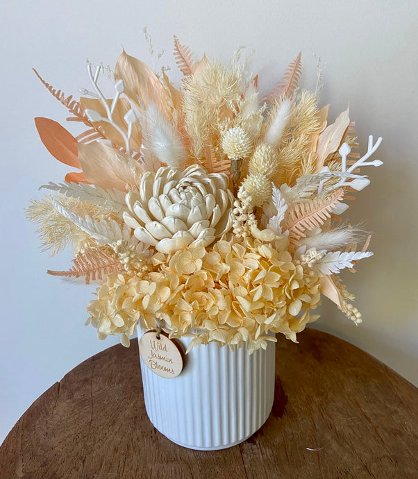 Peaches and cream is created using dried, preserved and faux flowers and displayed in a ribbed ceramic pot. It's subtle tones of peach and white will add a pretty touch to any room in the home or office and is also the perfect size for Nursing Homes and Hospitals. Approx size is 30cm x 20cm including pot. Sutherland Shire delivery. Sydney wide delivery. Australia wide delivery.