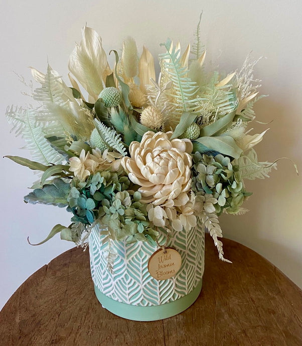 Serene Beauty is created using dried, preserved and faux flowers and displayed in a green and white patterned pot. It's natural tones of greens, aqua and white will add a serene touch to any room in the home or office. Approx size is 30cm x 25cm including pot. Sutherland Shire delivery. Sydney wide delivery. Australia wide delivery.