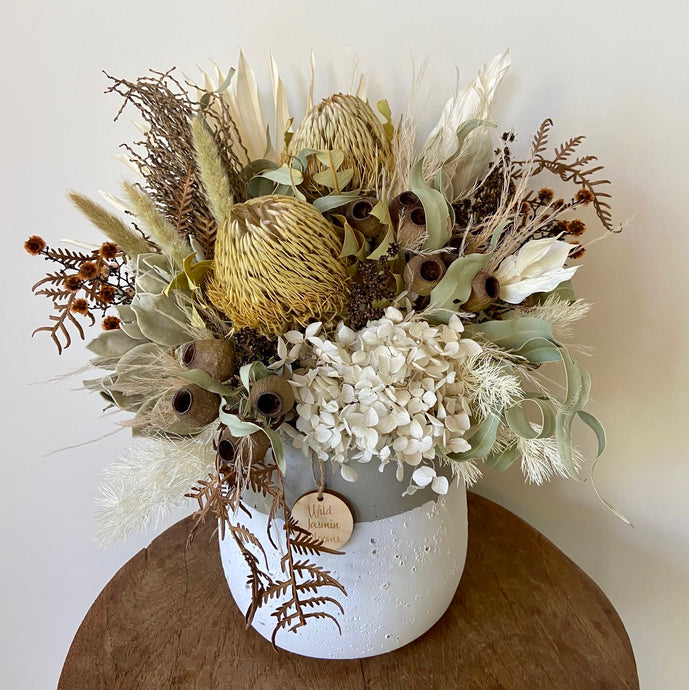 Wild Wind Dance is created using dried, preserved and faux flowers and displayed in a white and grey pot. 'It's natural colour tones of brown, green and white will add a whimsical statement to any room in the home or office. Approx size is 35cm x 30cm including pot. Sutherland Shire delivery. Sydney wide delivery. Australia wide delivery.