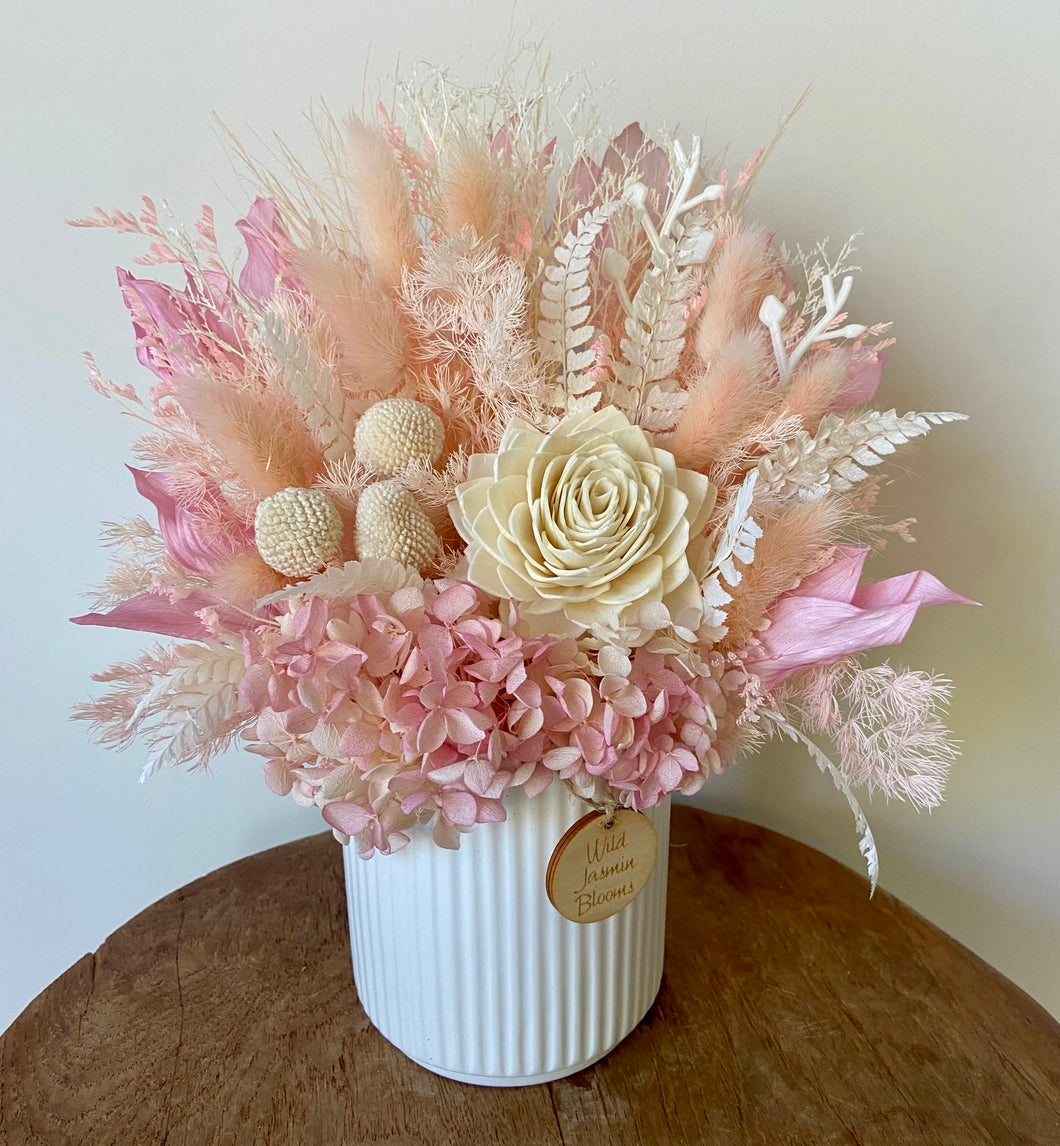 Bubblegum is created using dried, preserved and faux flowers and displayed in a ribbed ceramic pot.  It's soft tones of pink and white will add a pretty touch to any room in the home or office and is also the perfect size for Nursing Homes and Hospitals. Approx size is 30cm x 20cm including pot. Sutherland Shire delivery. Sydney wide delivery. Australia wide delivery.