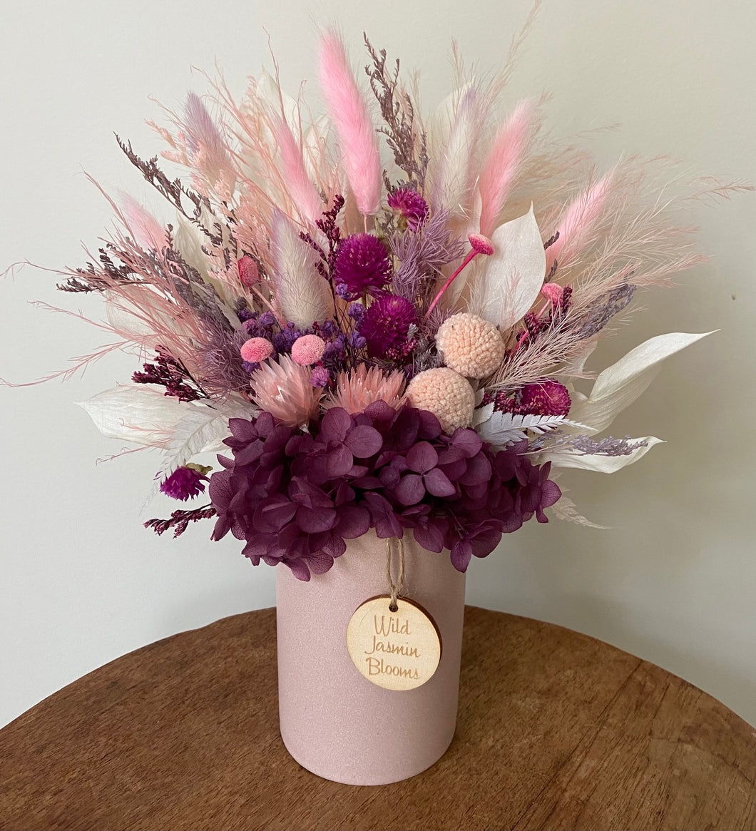 Plum Bliss is created using dried, preserved and faux flowers and displayed in a  ceramic pot. Its plum, pinks and mauve tones, add a deep warmth of colour to any room, home or office. Approx size is 28cm x 20cm including pot. Sutherland Shire delivery, Sydney wide delivery. Australia wide delivery.