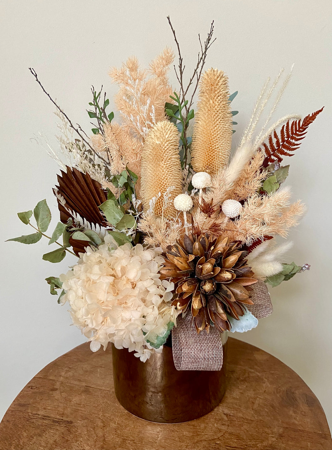 Golden Sun is created using dried, preserved and faux flowers and is displayed in a gold ceramic pot. Perfect display for a neutral home or office to bring a little warmth. Approx size is 40cm x 30cm including pot. Sutherland Shire Delivery. Sydney Delivery. Australia wide Delivery.