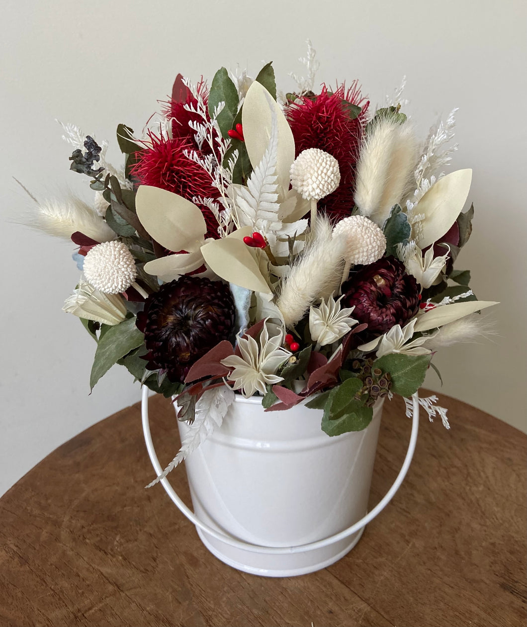 Petite Crimson Bucket is created using dried, preserved and faux flowers and displayed in a metal bucket.  Small in stature but big in charm! Approx size is 25cm x 20cm including bucket. Dried flower arrangement. Sutherland Shire Deliveries. Sydney Deliveries. Australia wide deliveries.
