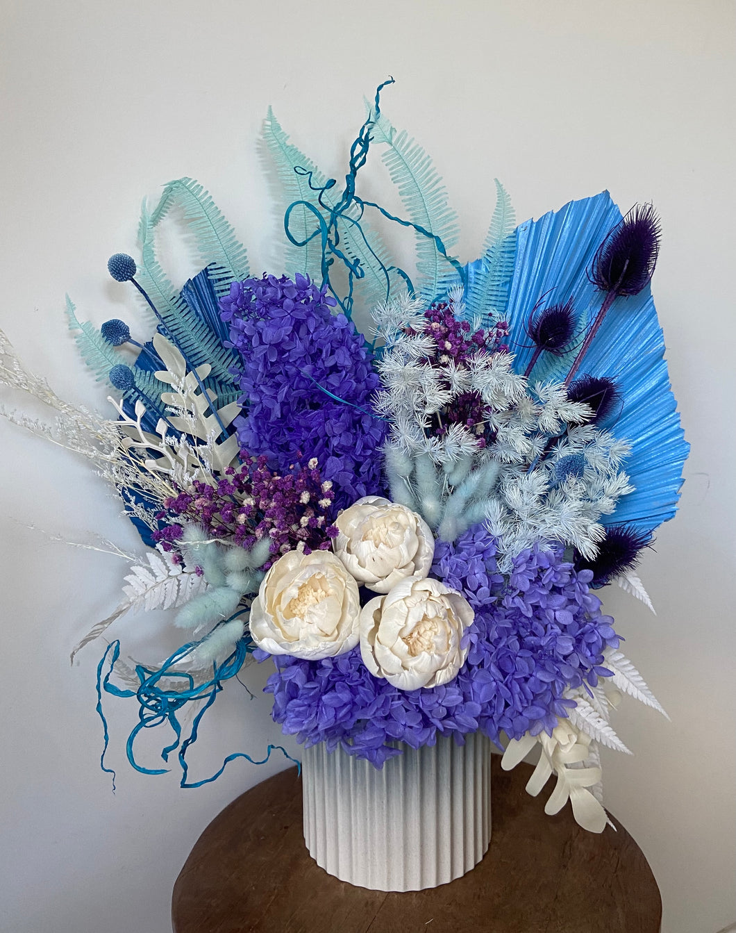 Night Sky is created using dried, preserved and faux flowers and displayed in an ombre pot. For the lovers of colour, this arrangement is created with blues, purples and white. Approx size is 60cm x 45cm including pot. Due to the size of this arrangement, delivery is only available within the Sutherland Shire. For deliveries outside this area please message me.