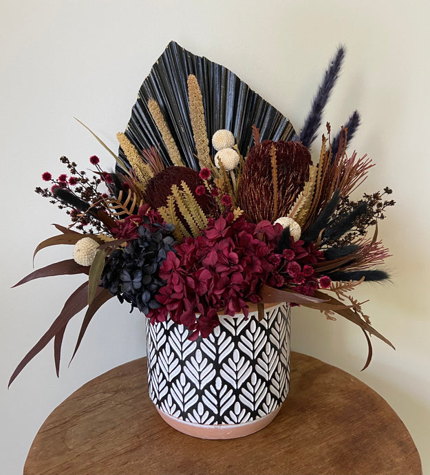 Port Wine is a dried, preserved and faux flower arrangement displayed in a stylish patterned black and white pot. Its compact style makes a gorgeous side table display for home, office or even hospital or Nursing Home. Its deep rich colour tones gives off a warm vibe, much like Port Wine itself! Approx size is 40cm x 30cm including pot. Delivery Sutherland Shire. Delivery Sydney wide. Delivery Australia wide.