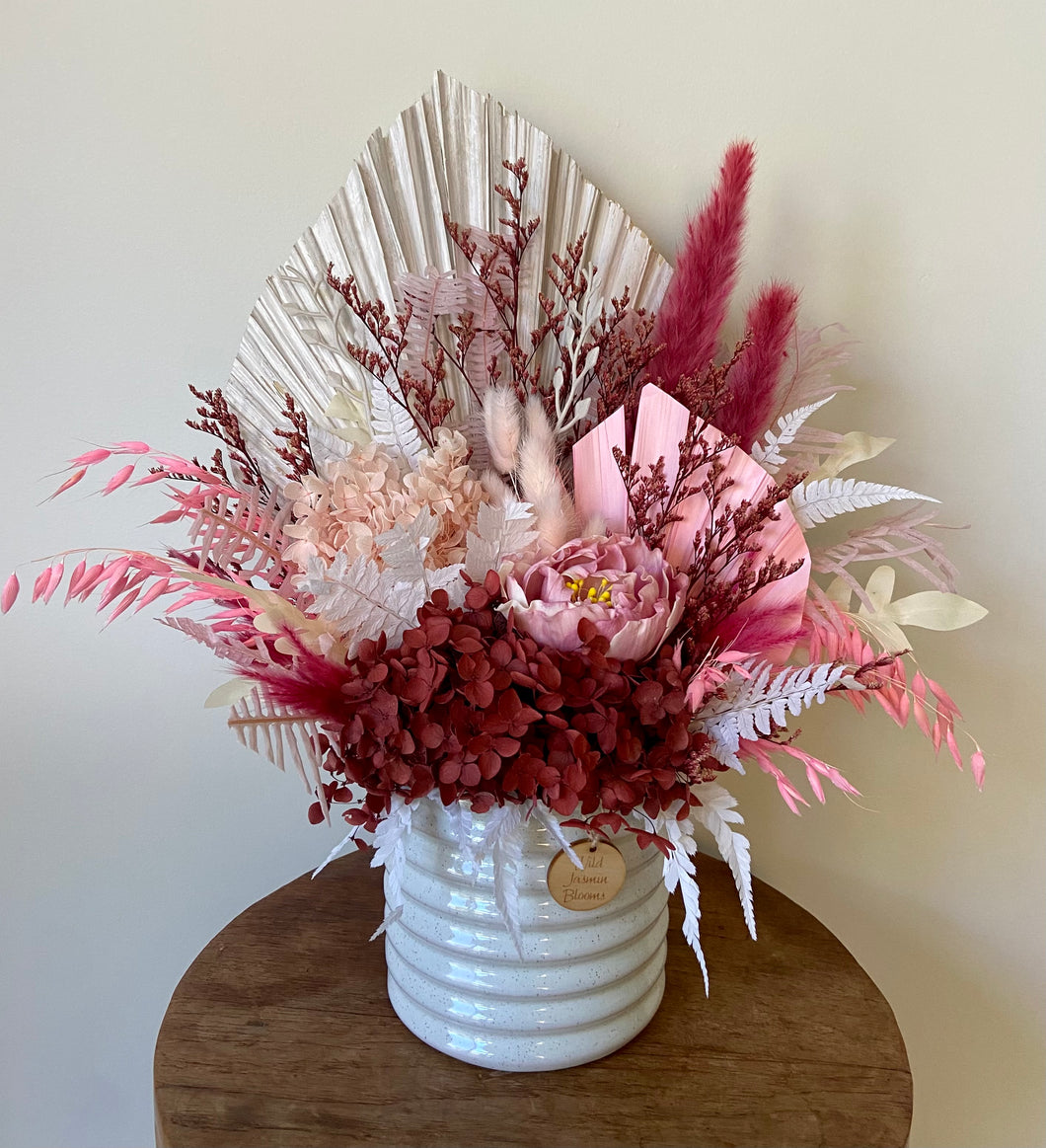 Cherry Blossom is created using dried, preserved and faux flowers and displayed in a ribbed ceramic pot. Its deep pinks and cherry tones, add a deep warmth of colour to any room, home or office. Approx size is 45cm x 40cm including pot. Sutherland Shire Delivery. Sydney wide delivery. Australia wide delivery.