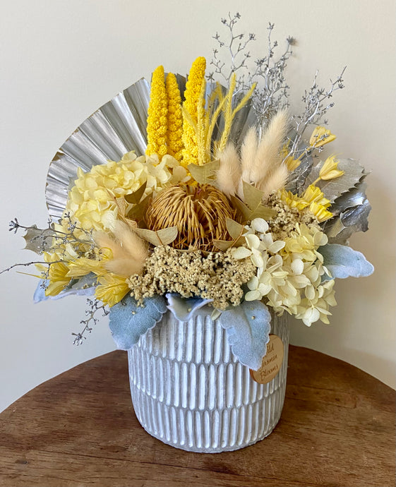 Lemon Sorbet is created using dried, preserved and faux flowers and displayed in a ribbed concrete pot. Its vibrant yellow tone is a perfect mini arrangement to add a pop of colour to any space. Great size for Nursing Homes and Hospitals too. Approx size is 30cm x 28cm including pot. Sutherland Shire Delivery. Sydney wide delivery. Australia wide delivery.